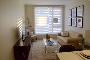 Apartamento premium, 1 cama Queen e sofá-cama, banheiro privativo | Sala de estar | TV de tela plana