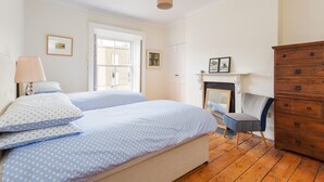 Quarto com duas camas, cômoda de madeira, uma cadeira e lareira.