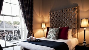 A hotel room with a large bed, two bedside lamps, a window with curtains, and a view of the outside. - The Bono Suite- hiphipstay (Dublin)