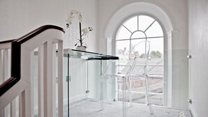A modern interior with a clear glass table, a chair, and a vase with flowers. - The Bono Suite- hiphipstay (Dublin)