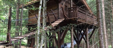 A treehouse with a wooden exterior, multiple levels, and a metal staircase.