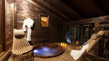 Eine Holzdiele mit Whirlpool, Holzliegen und einem kleinen Fenster.