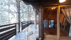 A wooden cabin with a wooden deck and a bench.