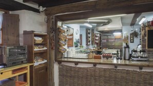 A rustic kitchen with a wooden counter, shelves with baked goods, and a variety of kitchen appliances. - Casa de la Montaña (Onis)