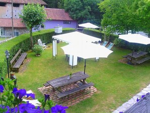 Un patio trasero con mesa de picnic, una parrilla de barbacoa y un área de estar techada.
