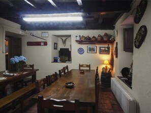 Un comedor con una larga mesa de madera, sillas, un jarrón con flores y una chimenea.