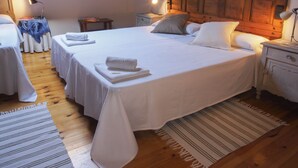 A hotel room with two beds, wooden floors, a striped rug, and a wooden headboard. - Casa de la Montaña (Onis)