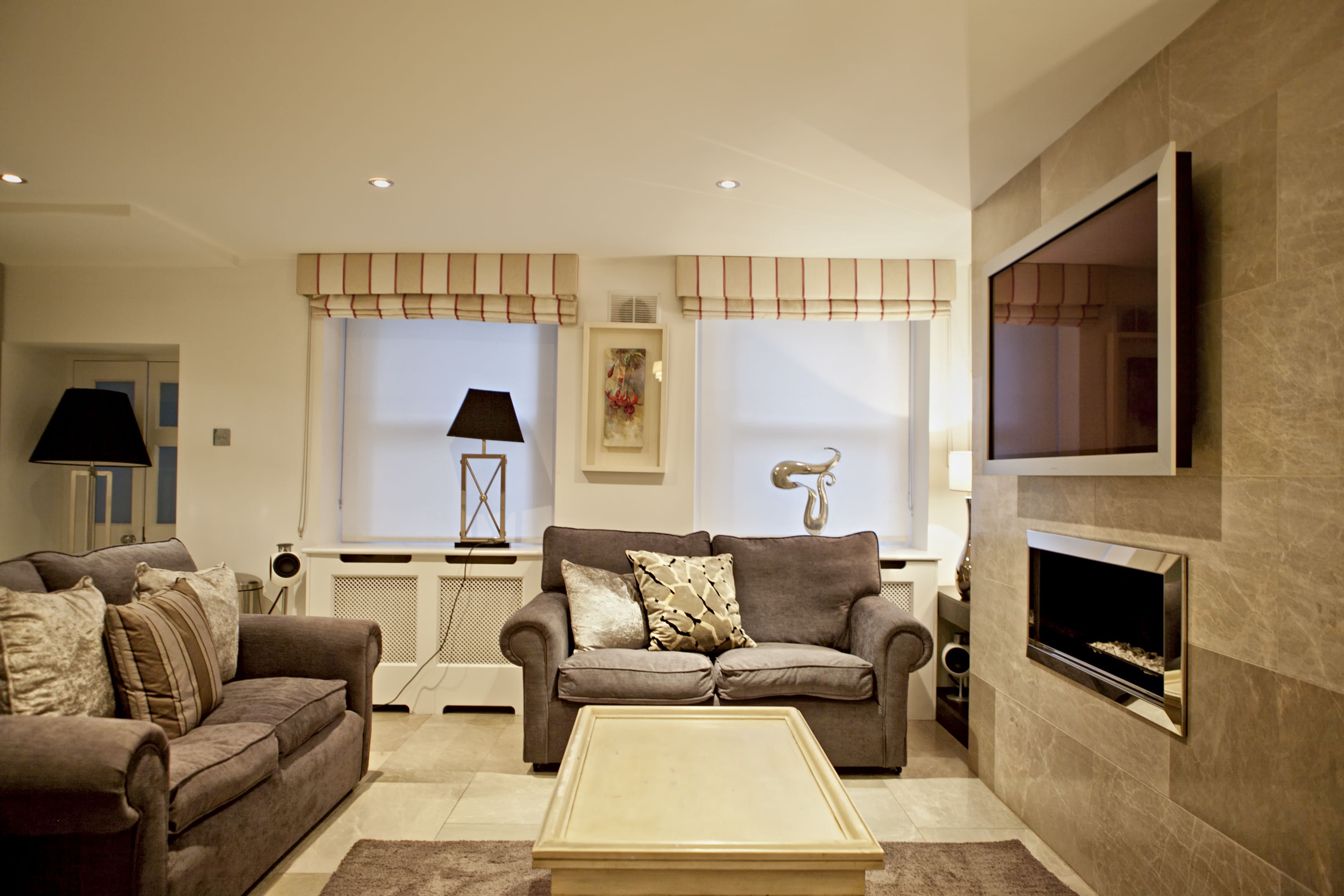 Ein modernes Wohnzimmer mit zwei Sofas, einem Couchtisch, einem Kamin und einem Wand-Fernseher.