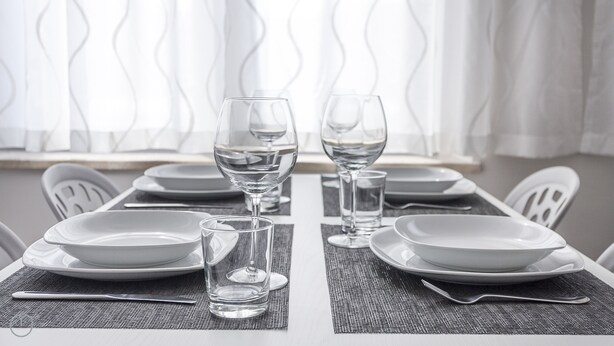 A dining table set with plates, glasses, and cutlery, with a view of a window with curtains. - Italianway - Cadorna 10 flat A (Milan)