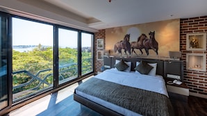 Une chambre moderne avec un grand lit, une vue sur la ville et une fresque représentant des chevaux.