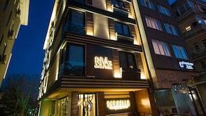 Un hôtel à plusieurs étages doté d’une façade moderne, d’une enseigne lumineuse et d’une entrée bien visible avec des marches.
