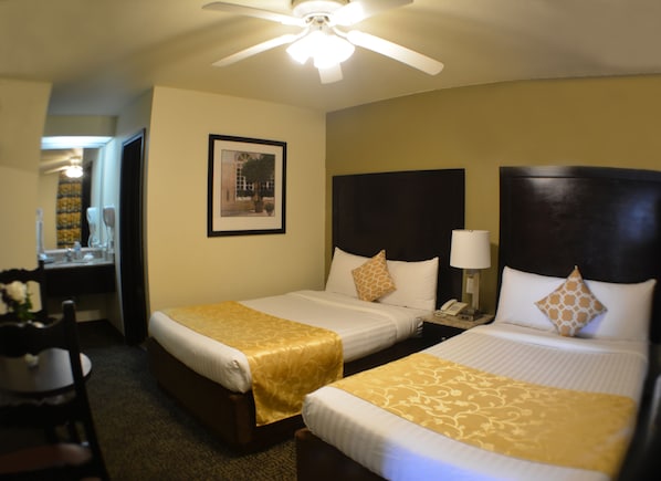 A hotel room with two beds, a desk, and a chair. - Hotel America (Tijuana)