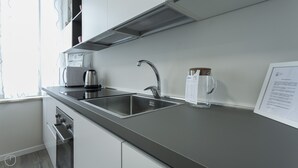 Eine moderne Küche mit Spüle aus Edelstahl, einem Wasserkocher und einer Kaffeemaschine.