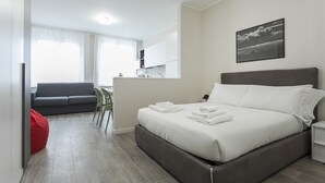 Ein modernes Hotelzimmer mit Bett, Sofa, Essbereich und Bad.