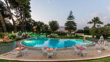 Una piscina al aire libre, sombrillas, sillones reclinables de piscina
