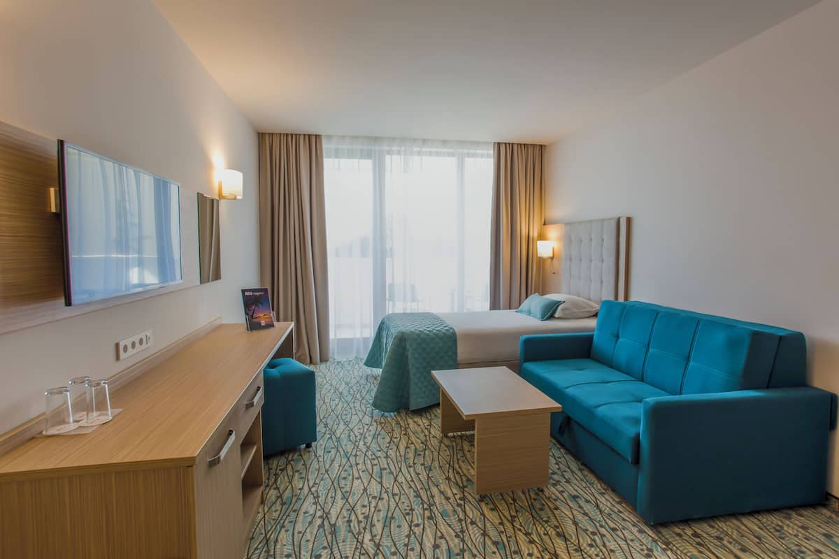 Ein Hotelzimmer mit Bett, einer Couch, einem Schreibtisch und einem Sessel.