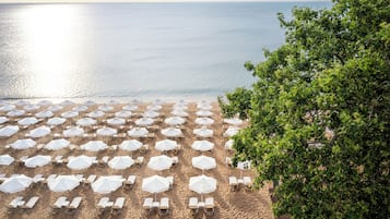 Praia particular, areia branca, espreguiçadeiras, guarda-sóis