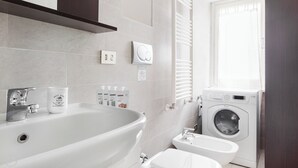 Uma casa de banho moderna com uma banheira grande, sanita e máquina de lavar roupa.