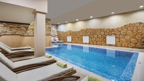 A swimming pool with lounge chairs and a stone wall. - Royal Park Hotel & Apartments (Bansko)