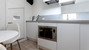 Eine kleine Küche mit eingebautem Backofen, einem weißen Tisch und einem Stuhl.