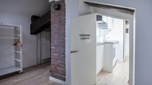 Ein Zimmer mit einem weißen Kleiderschrank, einer Backsteinwand und einer Tür mit der Aufschrift 'GJARDAROBA/STENDITOIO'.