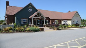 A building with a green facade, a red-tiled roof, and a sign that reads "MARSTON'S".