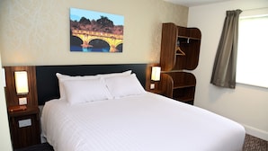 A neatly made bed with white linens in a hotel room.