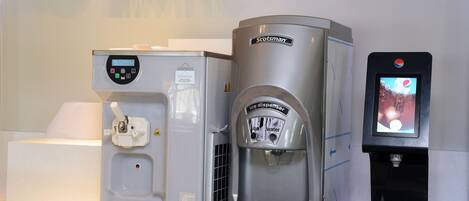 A water dispenser with a digital screen, a coffee machine, and a soft drink dispenser.