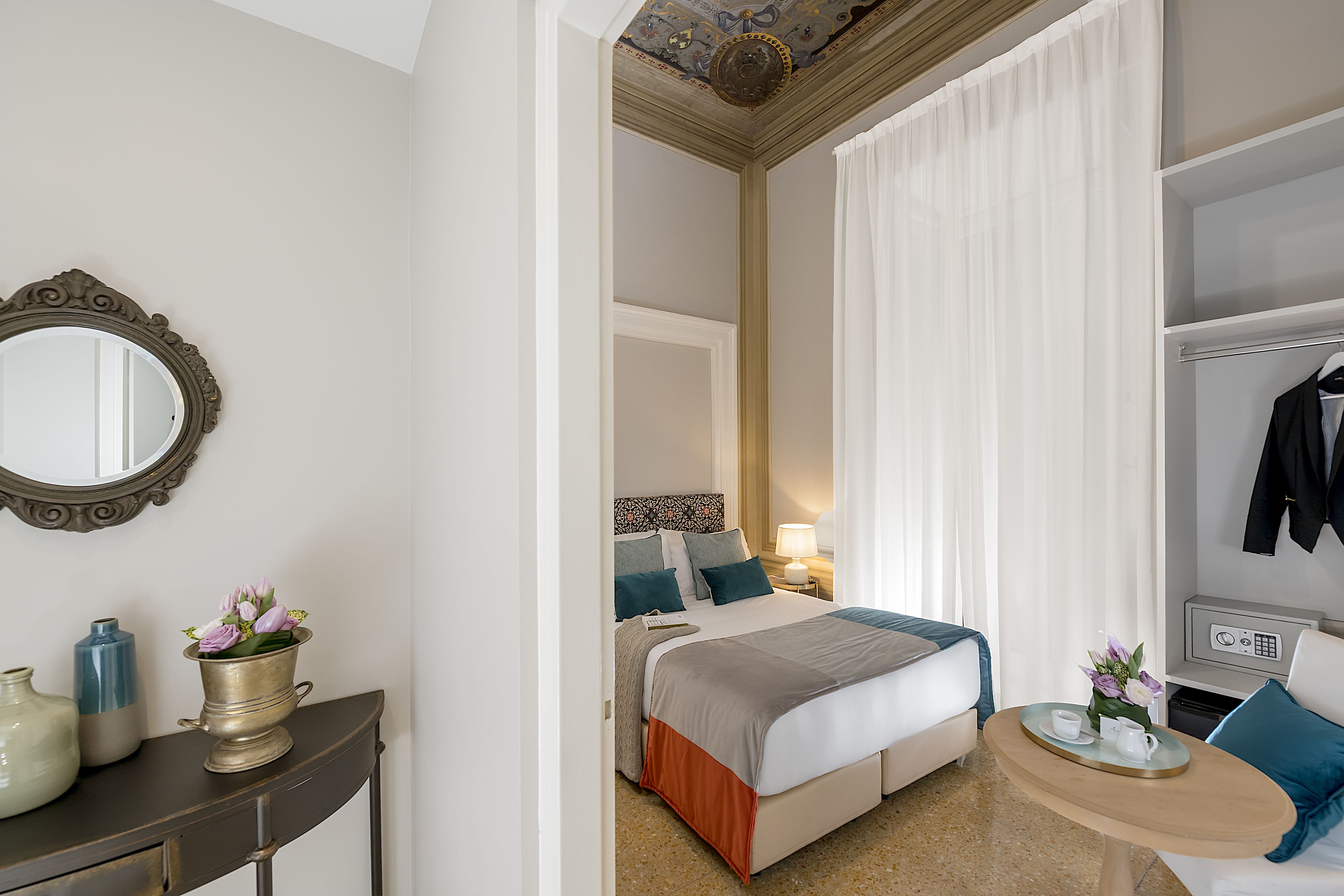 A hotel room with a bed, bedside table, and a mirror.