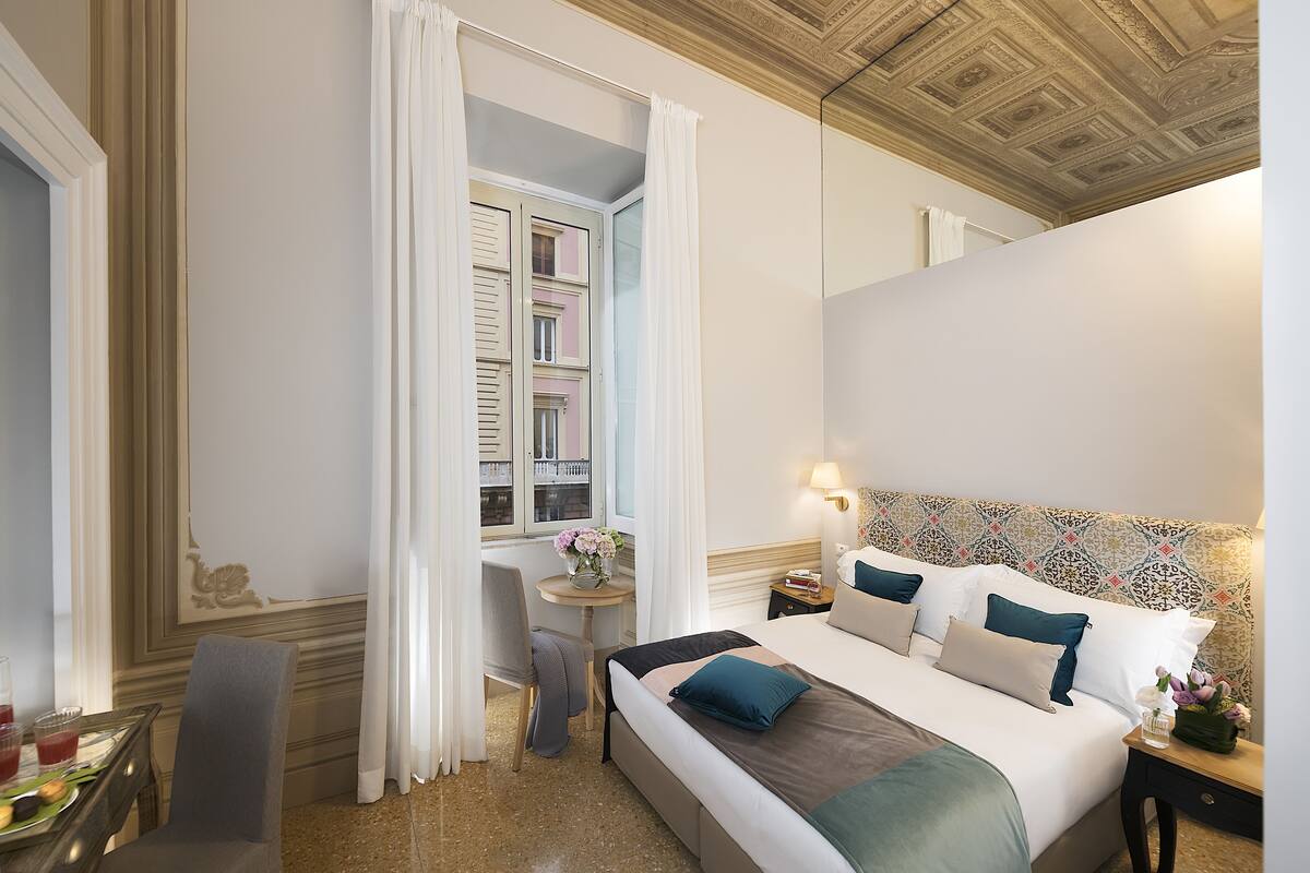 Habitación de hotel con cama, escritorio, silla y vistas al exterior.