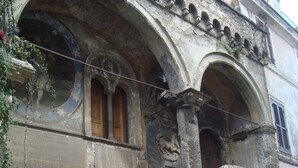 Un edificio histórico con puerta de madera, escalones de piedra y ventanas arqueadas.