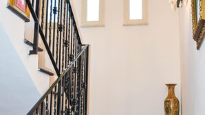 Una escalera con balaustres negros, un jarrón y un espejo en la pared.