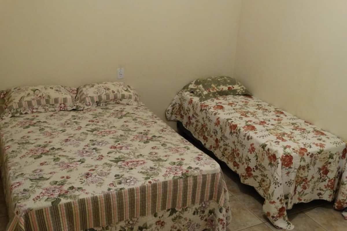 A small room with two single beds, each with floral bedding.