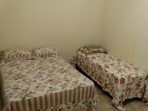 A small room with two single beds, each with floral bedding.