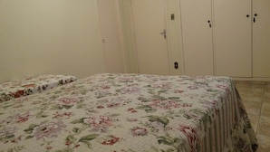 A bedroom with a floral bedspread, a door, and a wardrobe. - Pousada Santa Genebra (Campinas)