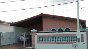 A two-story house with a gated driveway and a small front yard. - Pousada Santa Genebra (Campinas)