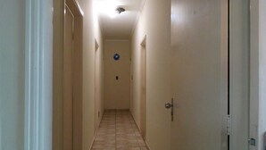 A narrow hallway with beige walls and a tiled floor. - Pousada Santa Genebra (Campinas)