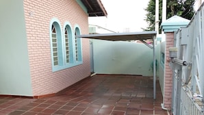 A covered outdoor area with a tiled floor, a brick wall, and a metal gate. - Pousada Santa Genebra (Campinas)
