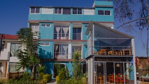 Ein zweistöckiges Gebäude mit blauer Fassade, zahlreichen Fenstern und einem Balkon.