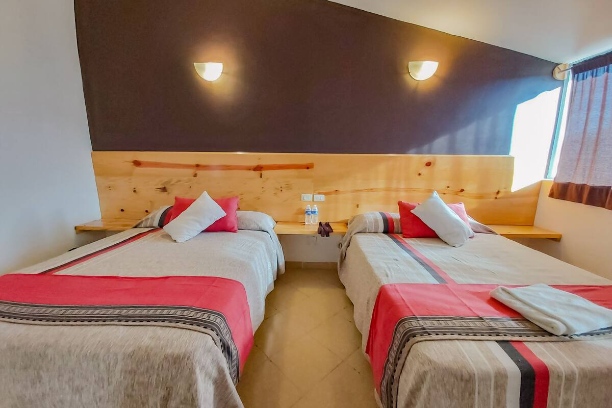 Een hotelkamer met twee bedden, houten hoofdeinden en nachtkastjes met lampen.