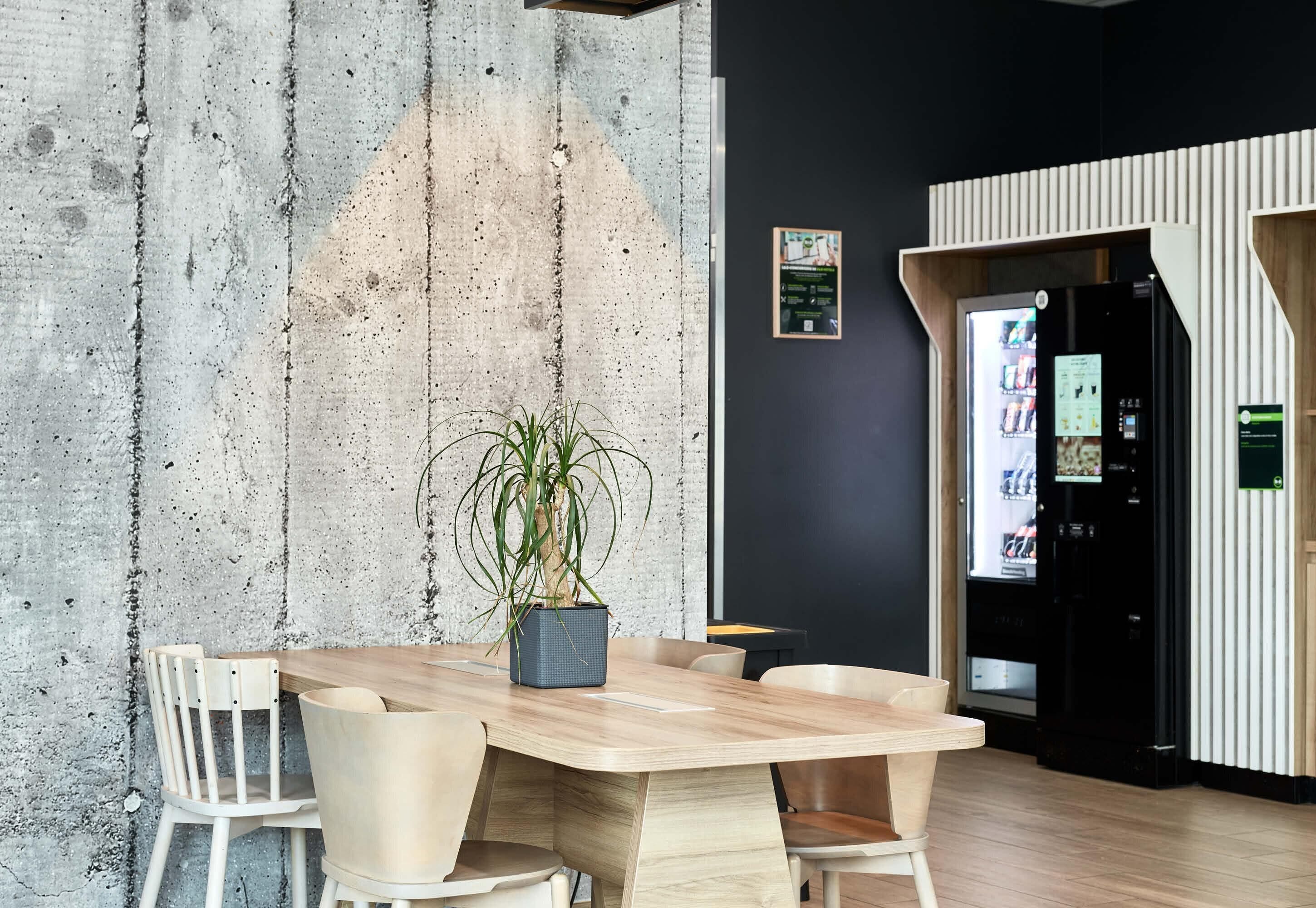 Une salle de réunion moderne avec un mur en béton, une table en bois et des chaises.