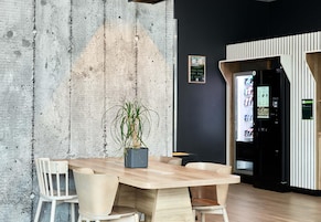 Una sala de reuniones moderna con pared de concreto, una mesa de madera y sillas.