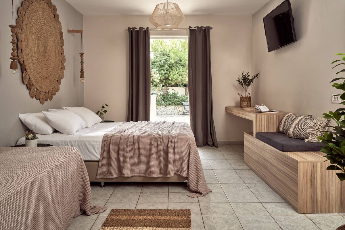 A modern bedroom with a bed, a sofa, a TV, and a large woven wall art piece.