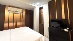 A hotel room with a bed, a TV, a wardrobe, and a built-in air conditioning unit. - The Victory View - Hostel - Adults only (Bangkok)