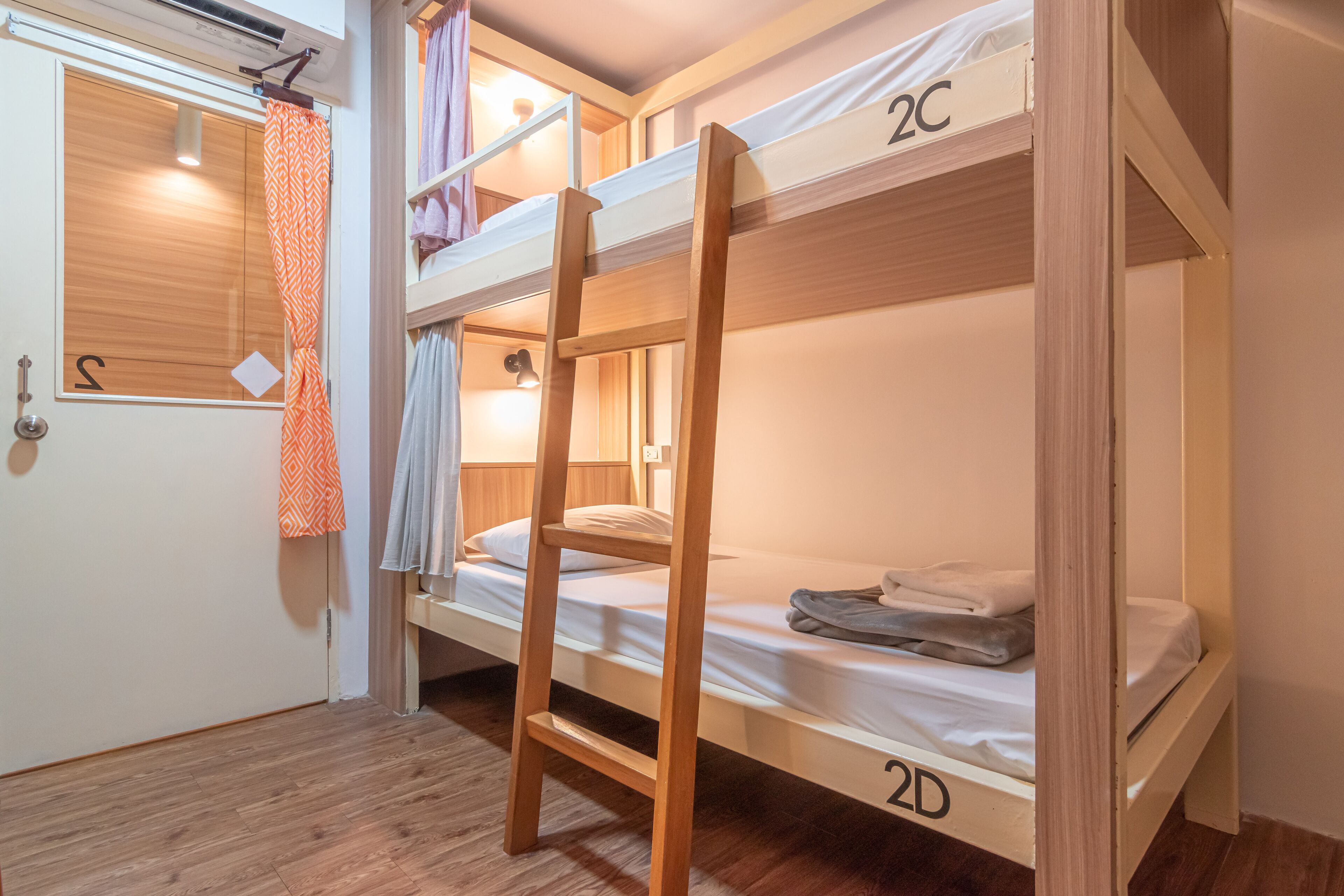 A bunk bed room with a wooden ladder, a door with a number 'S' sign, and a curtain.