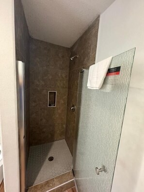 A glass-enclosed shower stall with a white towel hanging on the door. - Southwind Inn (Port Isabel)