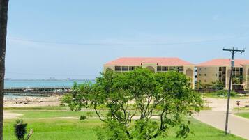 A coastal building with a red roof, surrounded by greenery and a clear view of the sea.