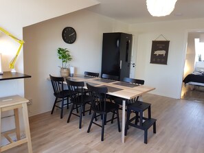 Una cocina moderna con una mesa de comedor, sillas, un refrigerador negro, un reloj y una planta.