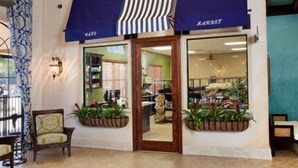 Une devanture de magasin avec un auvent bleu, une porte en bois et des plantes en pot.