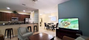 A modern kitchen with a refrigerator, microwave, and dining area with chairs and a table.